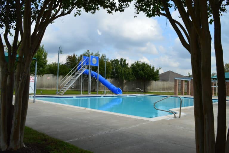 Sheffield community pool with a blue slide and shaded pavilion columns, Houston TX 77095