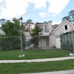 Fire-damaged brick Houston home behind a fence, illustrating why homeowners insurance matters