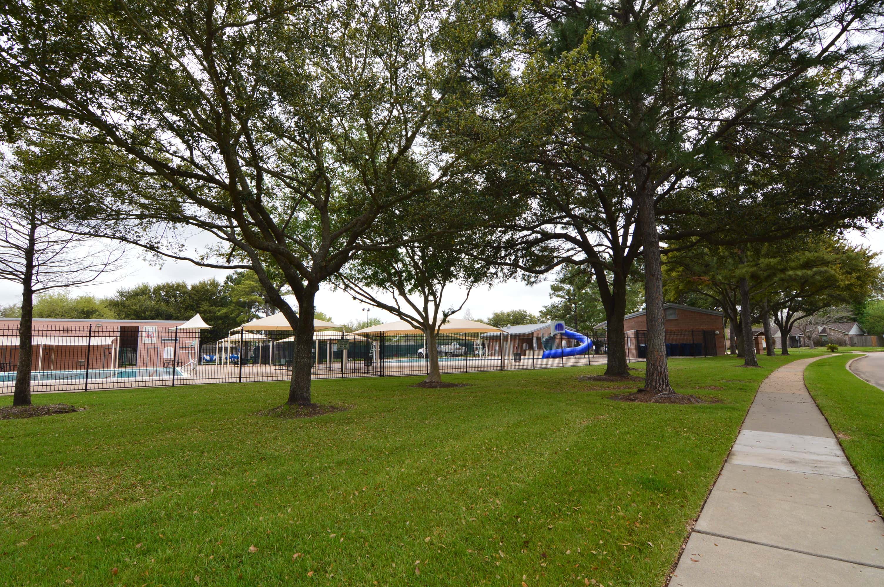 Open lawn, walking path and mature oaks beside the Concord Bridge pool complex, Houston TX 77041