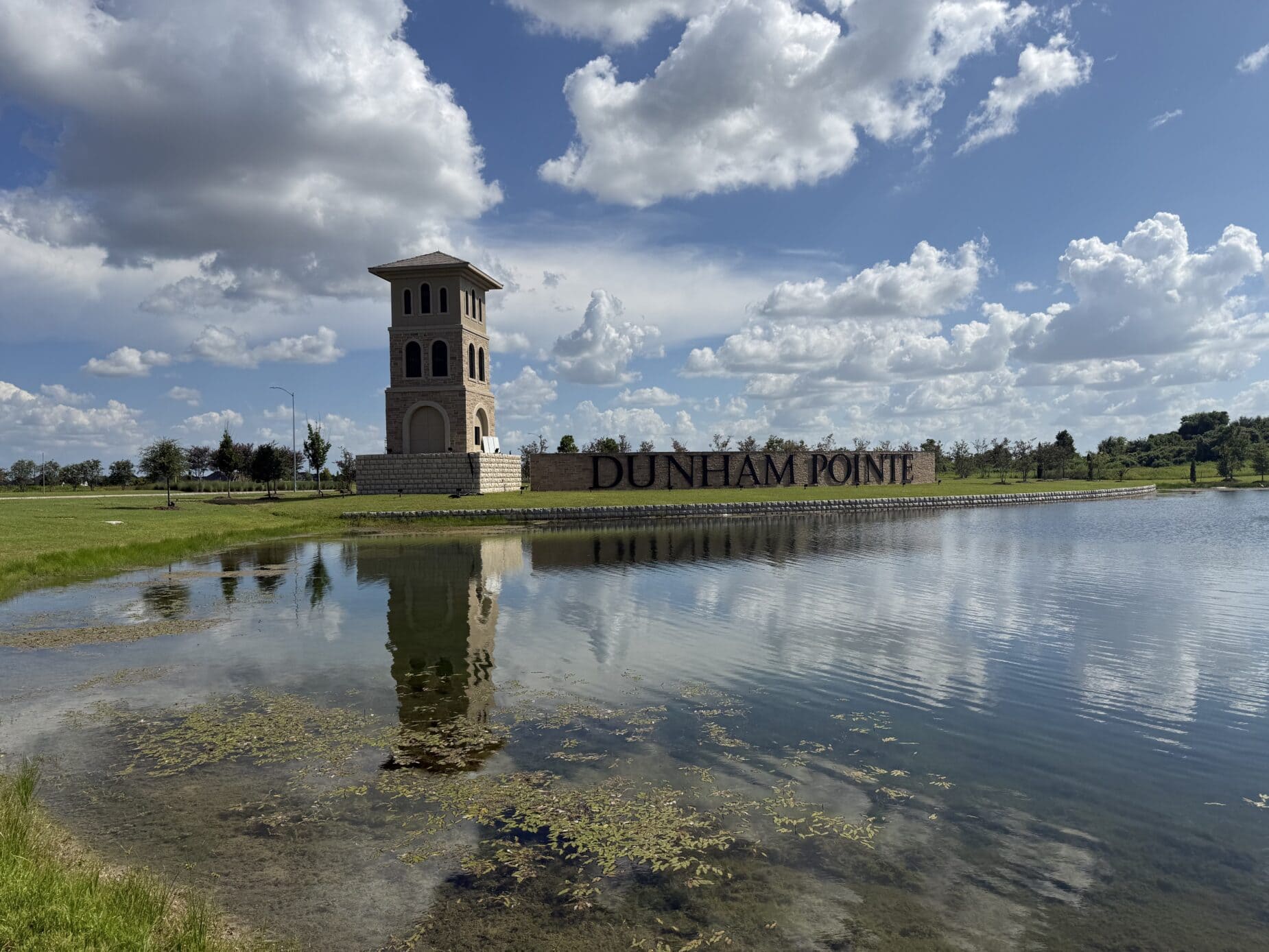 Dunham Pointe entrance sign and stone tower reflected in the community lake — Cypress, TX 77433