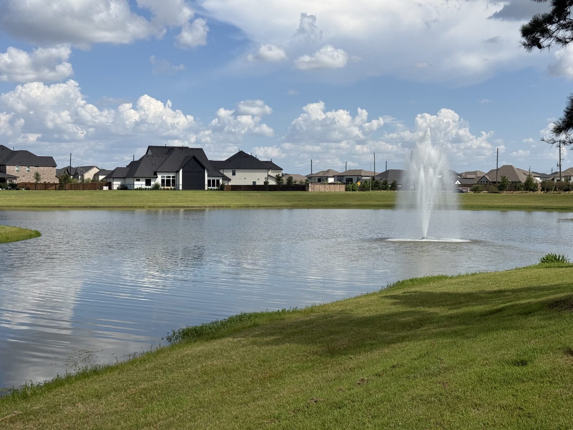 A Dunham Pointe detention lake with a center fountain and homes along the far shore — Cypress, TX 77433