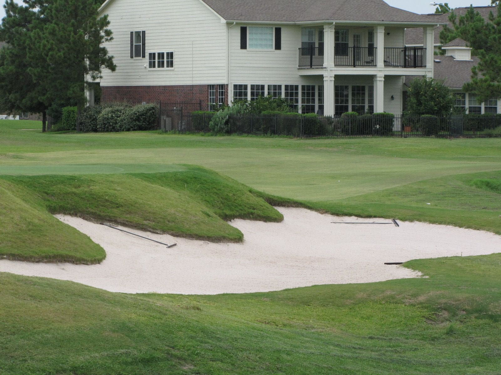 Houston National Golf Club green and bunker with Stone Gate homes behind it, Houston TX
