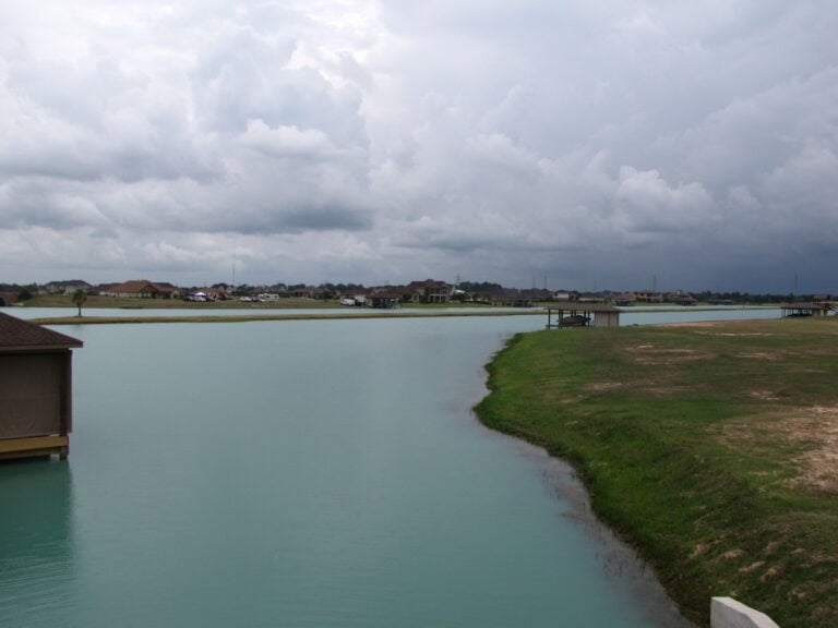 Channel between two Lakes of Katy lakes with a lakefront boathouse and grassy bank, Katy TX 77493
