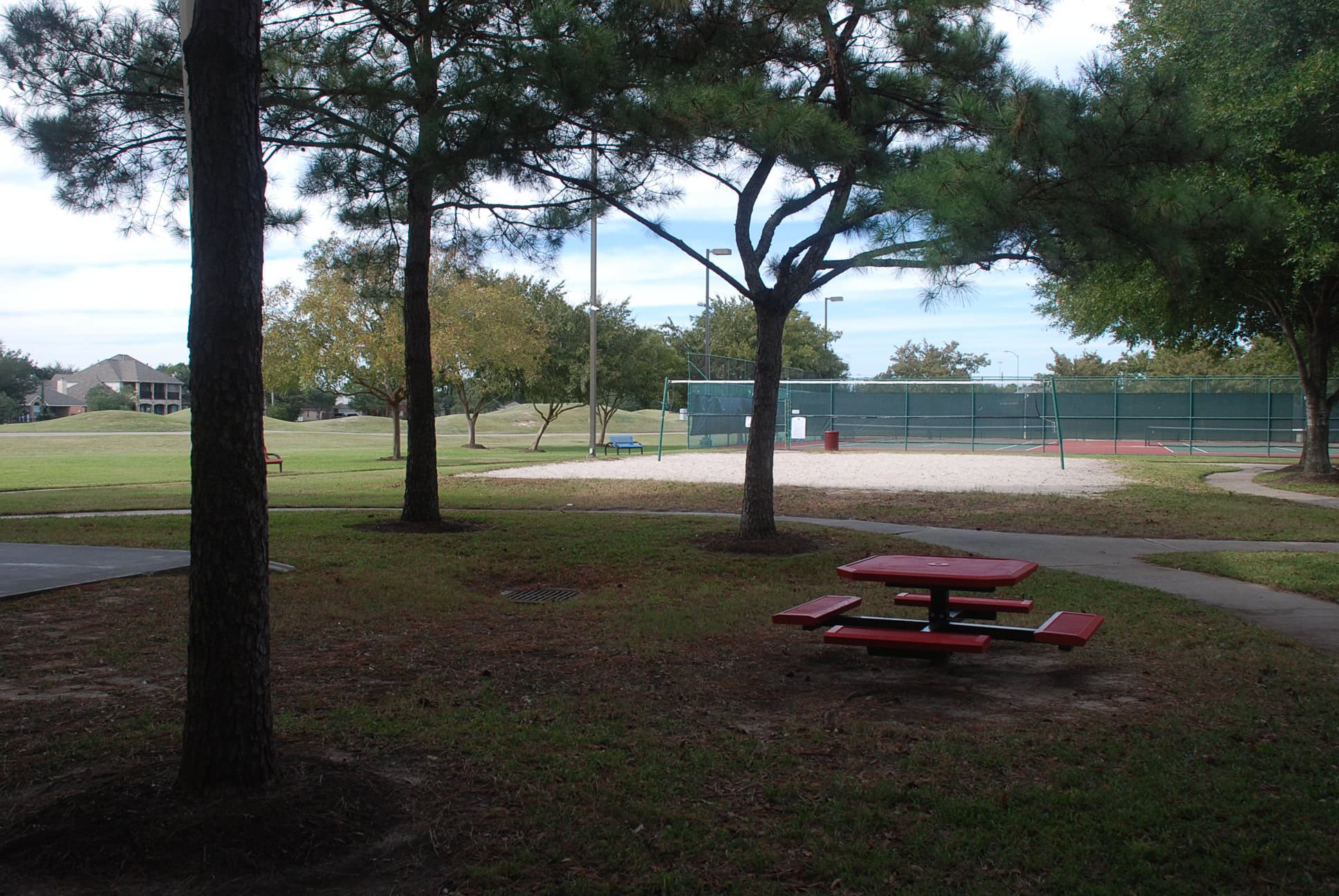 Sand volleyball court and picnic table under the trees at the Stone Gate recreation center