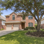 Two-story brick home with a mature oak tree in a Houston, Texas neighborhood, typical of homes for sale in Houston between $400,000 and $450,000