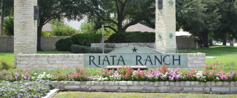 Riata Ranch entrance sign with limestone columns and flower beds, Houston TX 77095