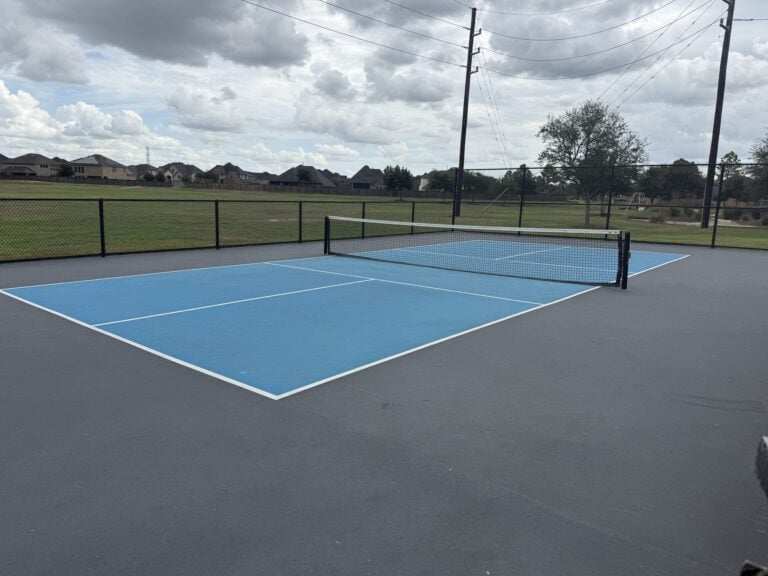 Pickleball court with a net and homes beyond at a Cane Island park, Katy TX 77493