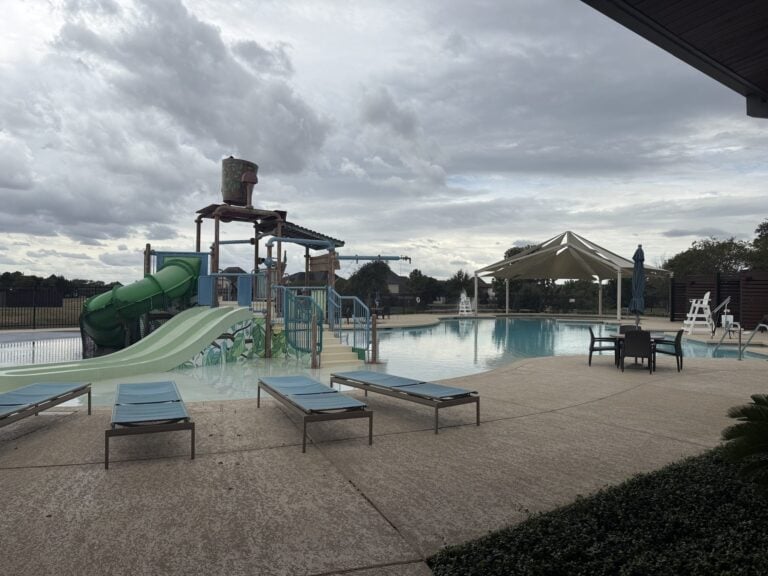 Resort pool with a water-play structure and lounge chairs at Cane Quarter, Cane Island, Katy TX 77493