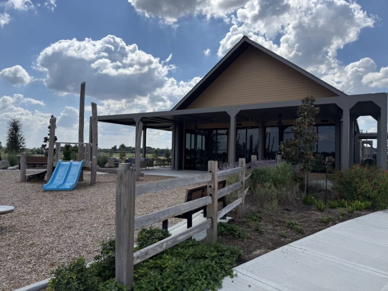 Wooden playground with a blue slide in front of a covered pavilion at Everly, Hockley TX 77447