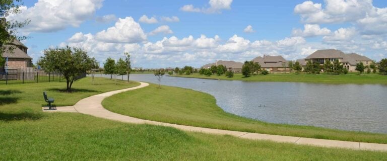 A walking path winding along a community lake with homes across the water in Fairfield, Cypress, TX 77433