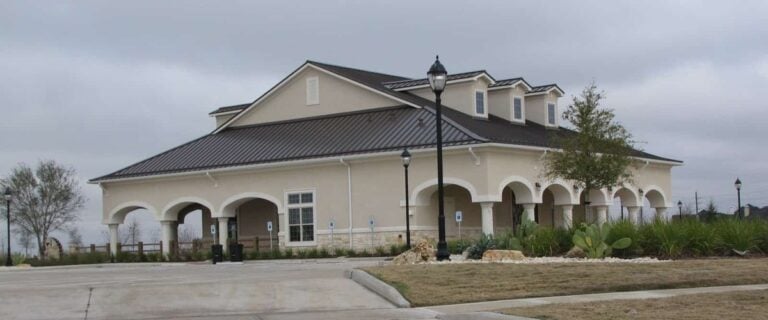 Firethorne community clubhouse with arched porches and a metal roof in Katy, TX 77494