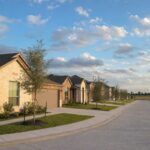 Hockley vs Cypress: a street of new brick-and-stone homes ending at open prairie along the US-290 corridor northwest of Houston