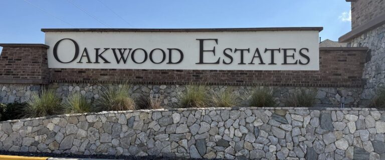 OAKWOOD ESTATES entry sign on a brick and stone monument wall, Waller TX 77484