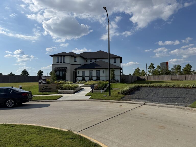 Two-story Shea Homes model with a white stucco and stone front, dark trim, and a Shea Homes sign by the walk, Hockley TX 77447