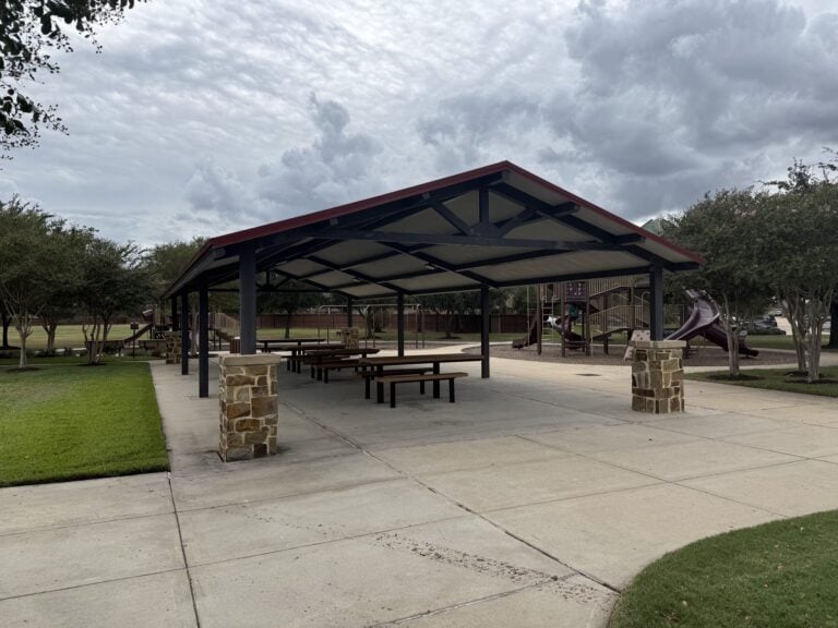 Covered picnic pavilion with a playground behind it in Ventana Lakes, Katy TX 77493