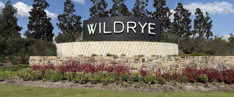 WILDRYE entry monument on a stone base with red and green landscaping, Waller TX 77484